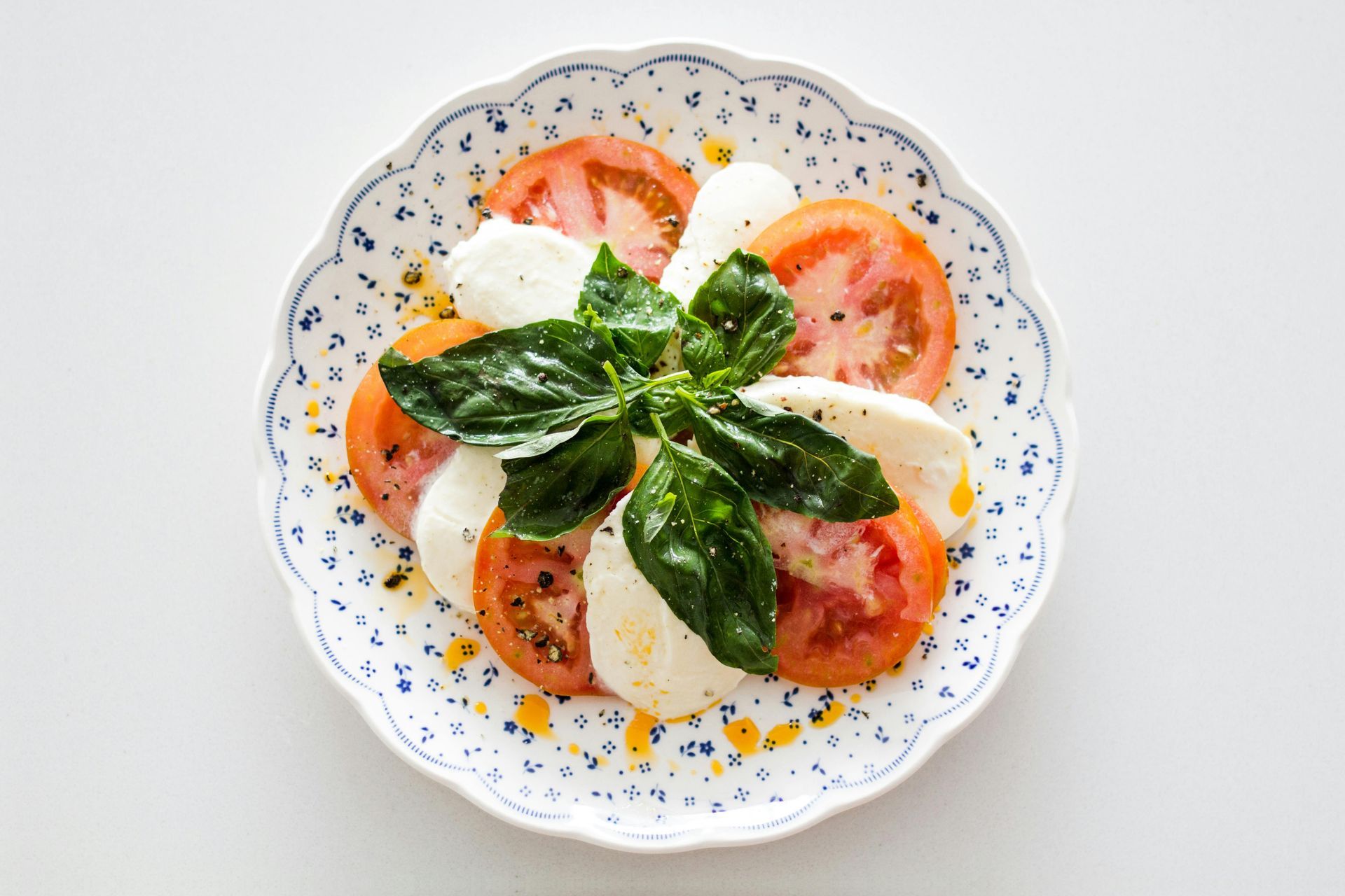 Ensalada Caprese: rodajas de tomate, mozzarella y albahaca en un plato decorativo.