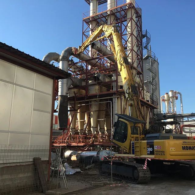 Una gran excavadora amarilla está estacionada frente a un edificio.