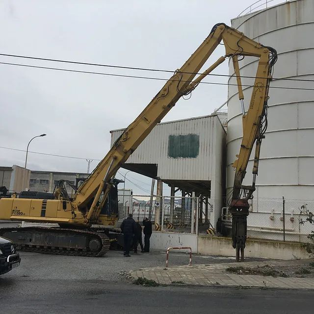 Una gran excavadora amarilla está estacionada frente a un edificio blanco.