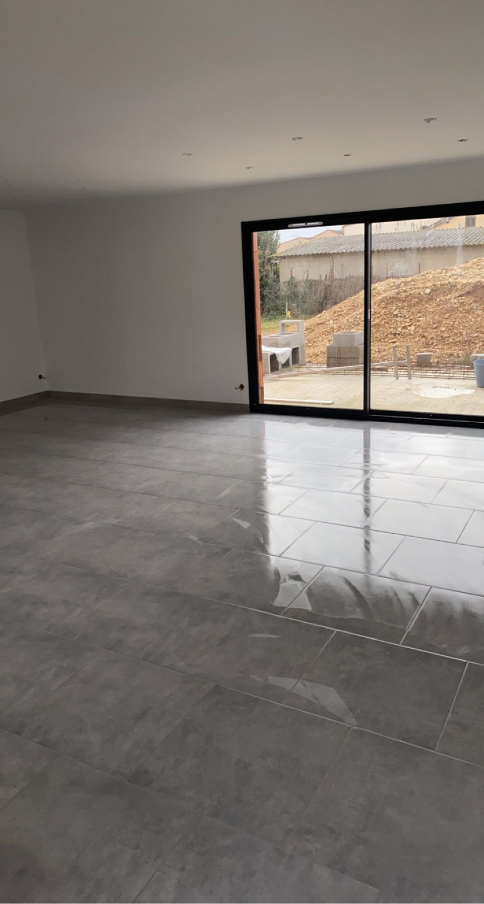 Pose d'un carrelage gris dans une maison en construction