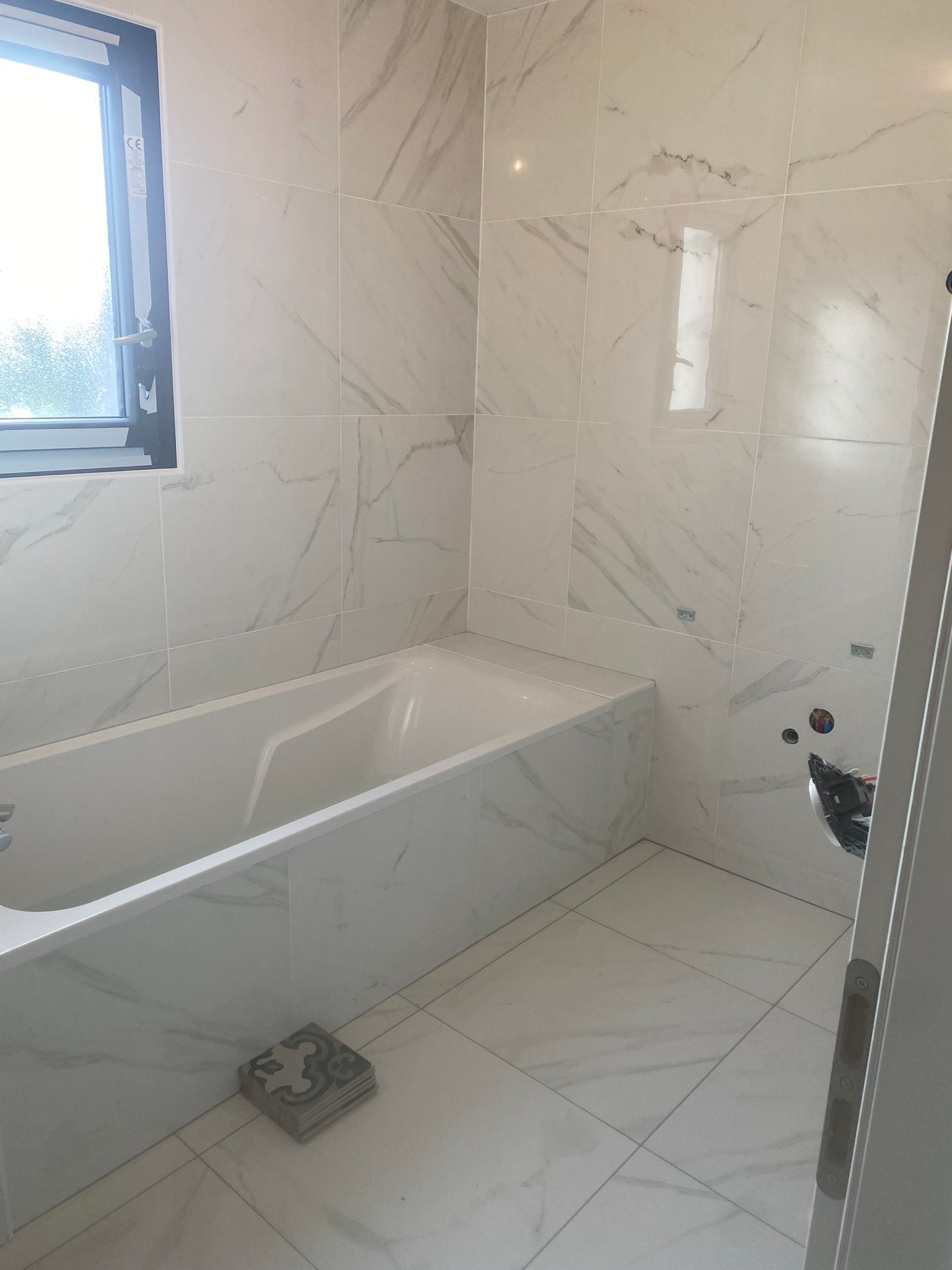 Salle de bain avec baignoire et carrelage effet marbre blanc