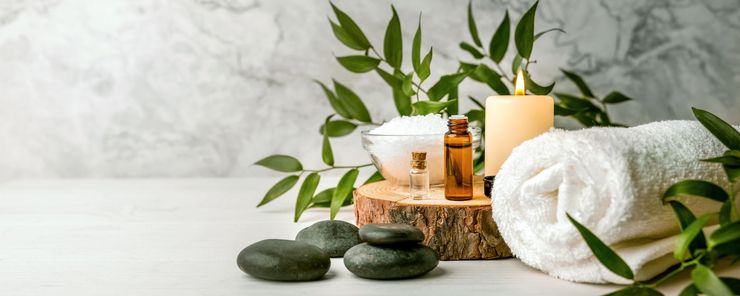 Installation de Spa : serviette roulée, bougie allumée, huiles essentielles, pierres et verdure.