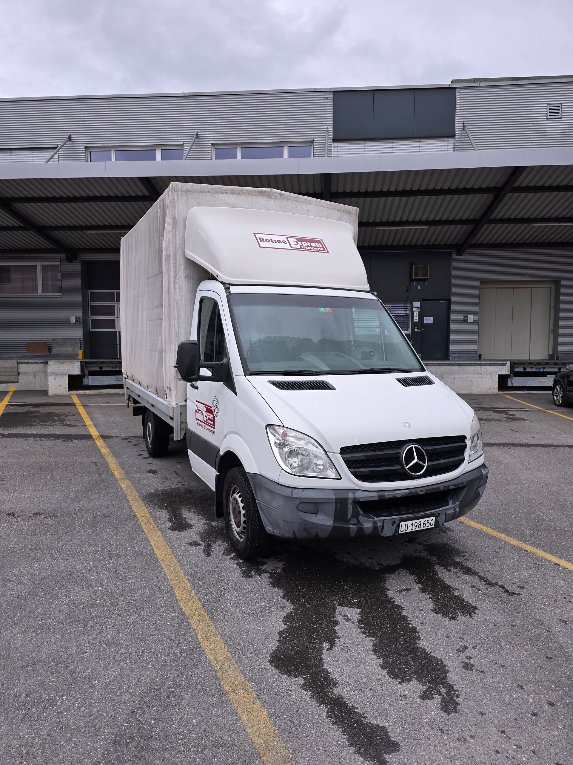 Zwei Männer laden Kisten in einen Lieferwagen.