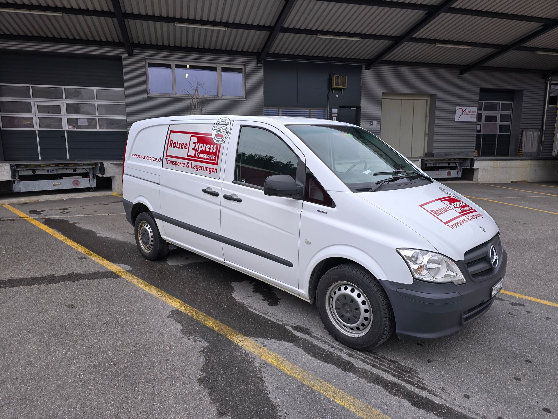 Zwei Männer laden Kisten in einen Lieferwagen.