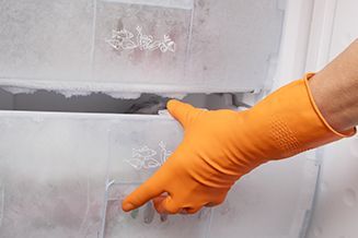 Una persona que lleva guantes naranjas está abriendo la puerta de un congelador.