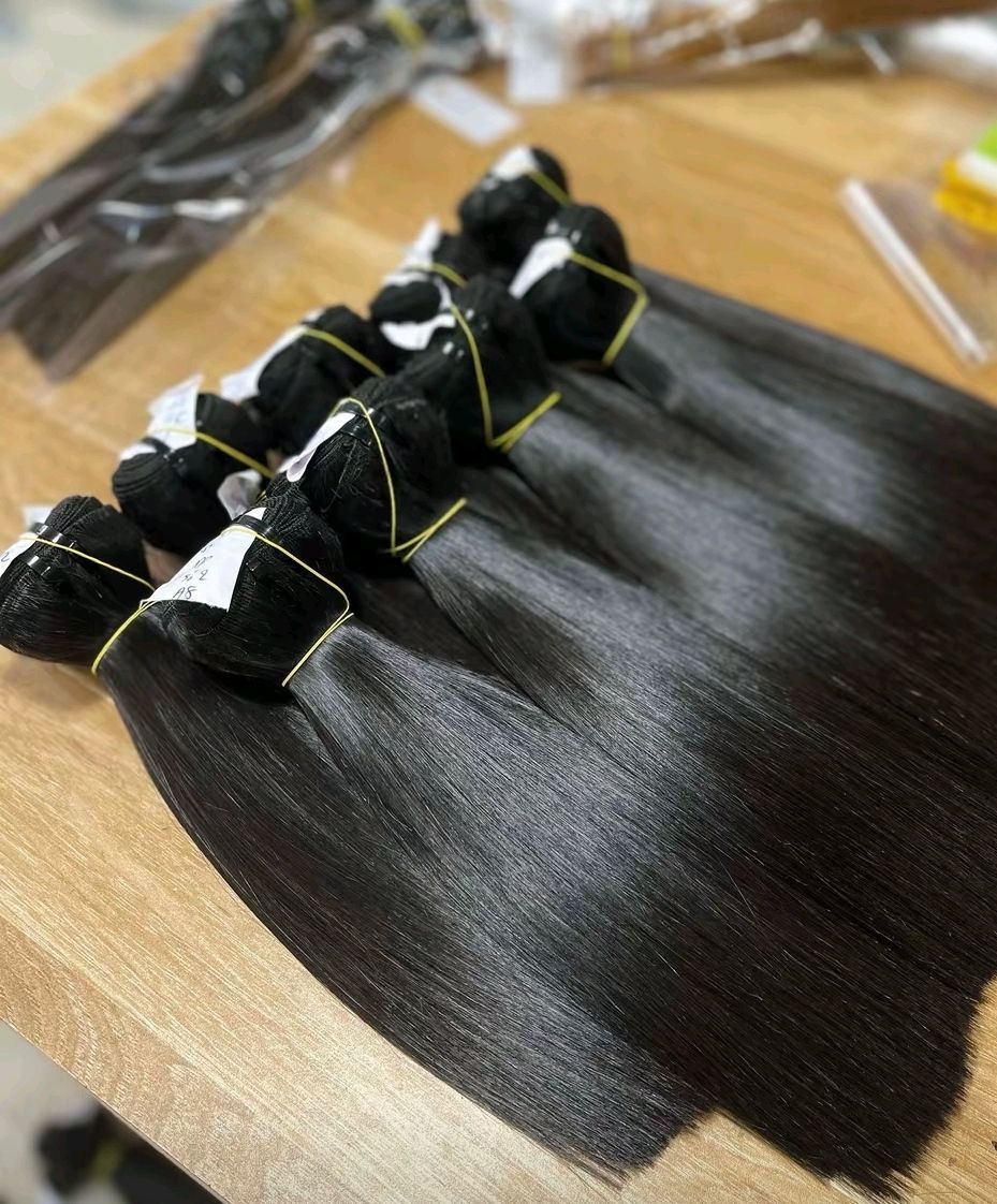 Des mèches de cheveux brillants et foncés, attachées par des élastiques dorés sur une surface en bois.