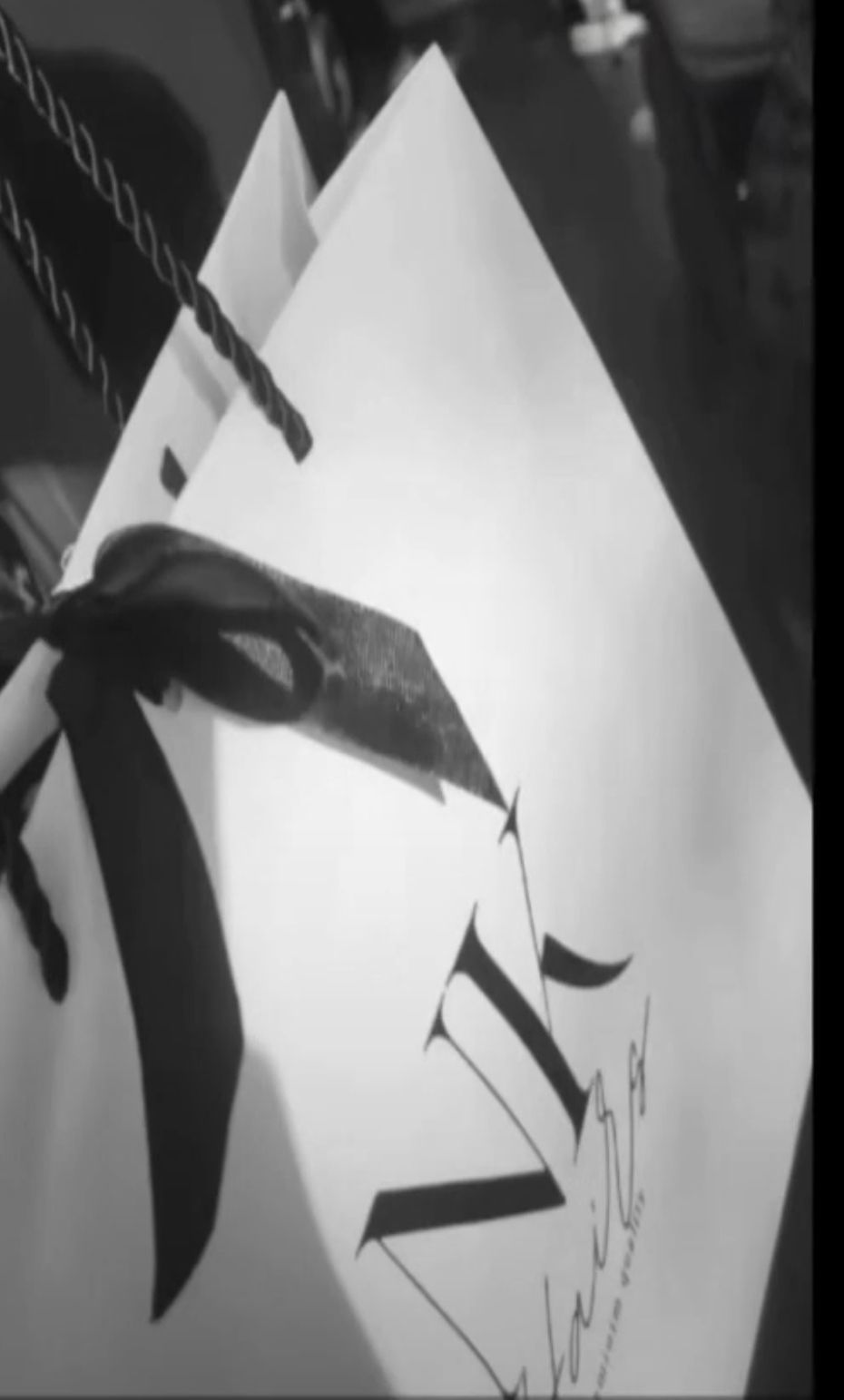 Boîte cadeau brune, nouée avec de la ficelle, posée sur un plateau tressé, sur une surface texturée.