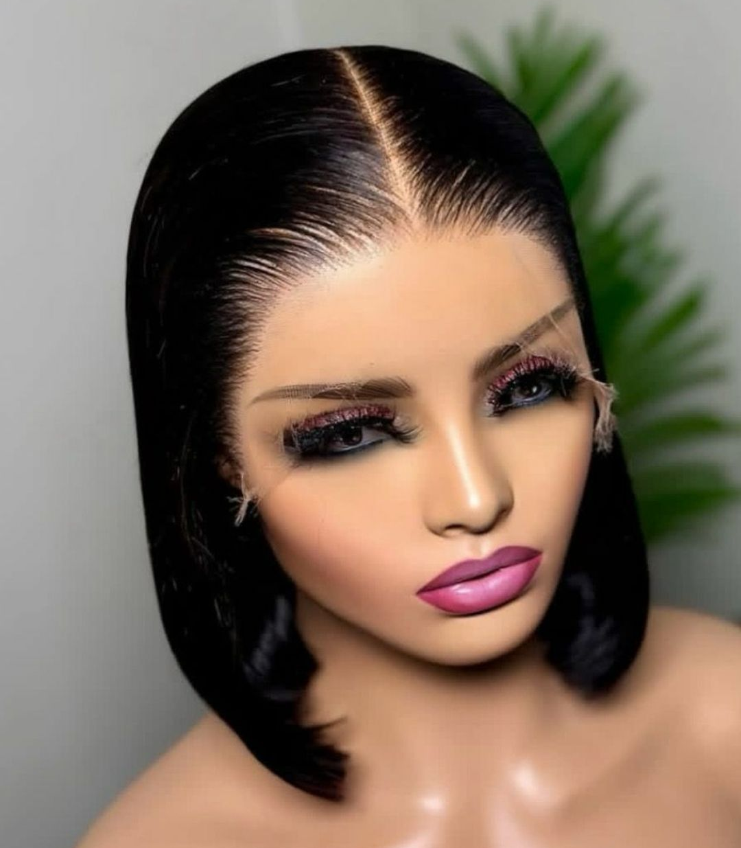 Cinq femmes vêtues de robes à motifs colorés posent, certaines bras dessus bras dessous, devant un fond orange.