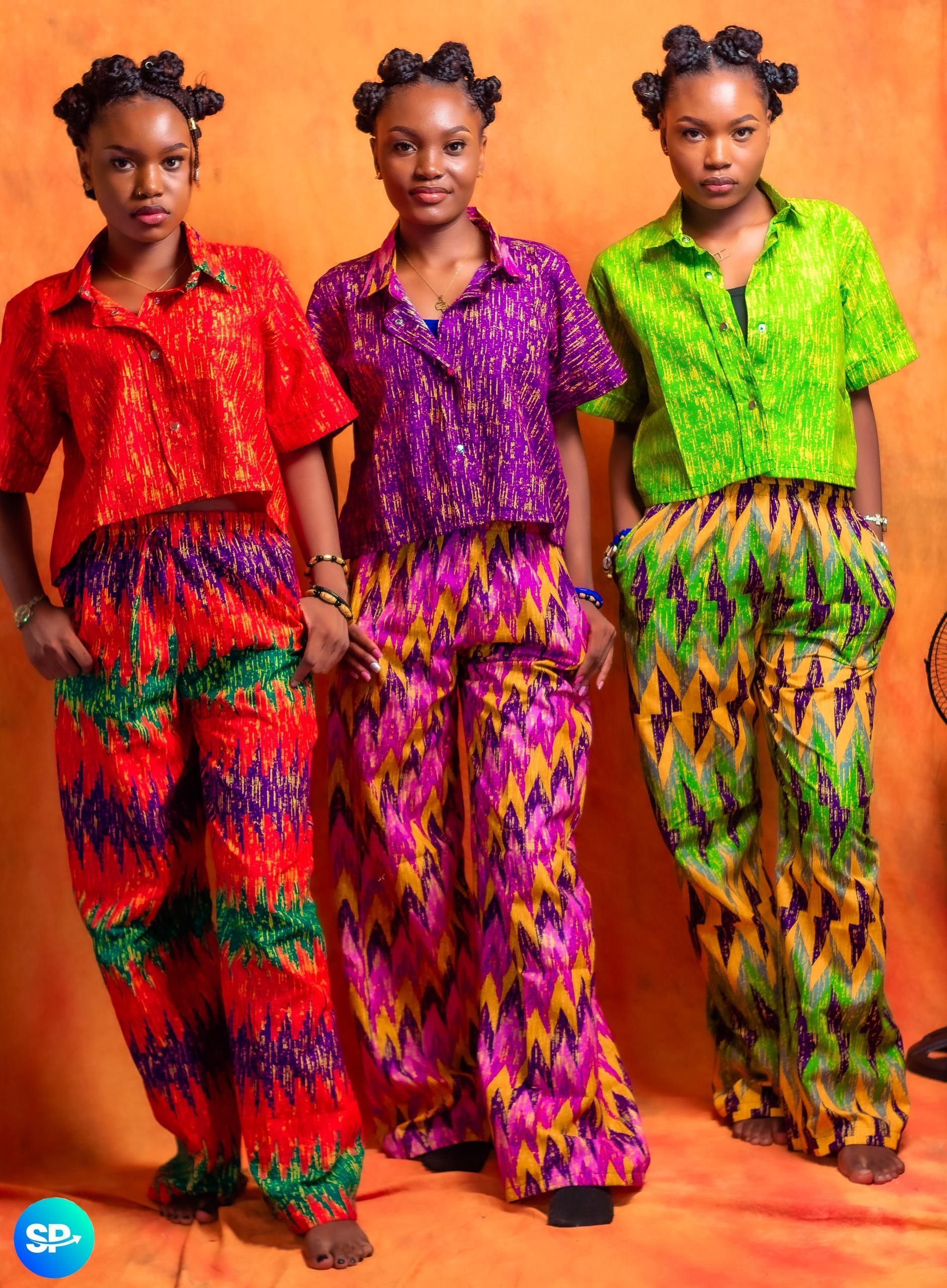 Trois personnes vêtues de chemises et de pantalons à motifs assortis, posant devant un fond orange.