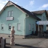 Ein grünes Haus mit einer Statue davor.