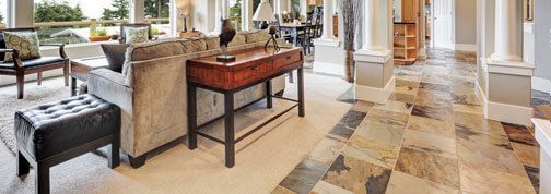 Ein Wohnzimmer mit Couch, Tisch und Stühlen und gefliestem Boden.