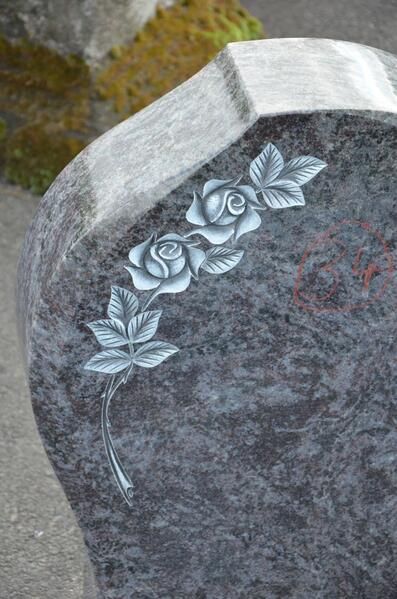 Ein Grabstein mit eingeschnitzten Rosen und Blättern.