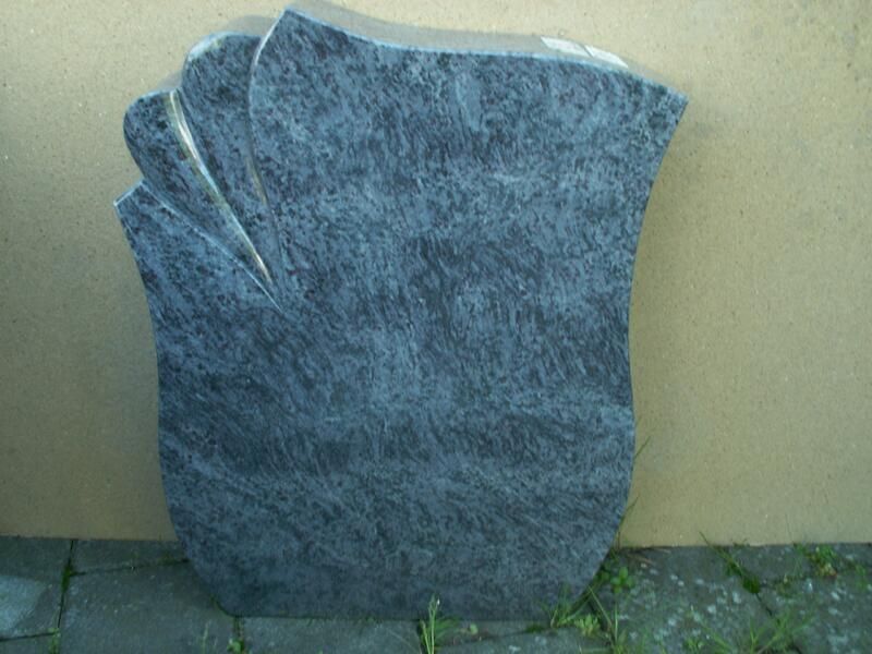 Ein großer grauer Stein liegt auf einem Gehweg vor einer Mauer.