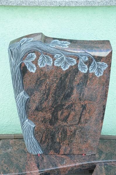 Auf einem Tisch steht ein Grabstein mit einem eingemeißelten Baum.