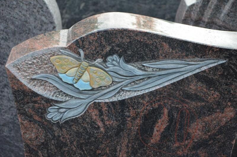 In die Seite eines Grabsteins ist ein Schmetterling geschnitzt.