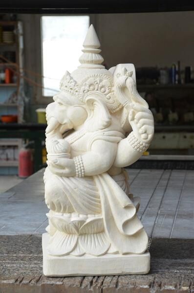 Eine weiße Statue einer Gottheit sitzt auf einem Holztisch.