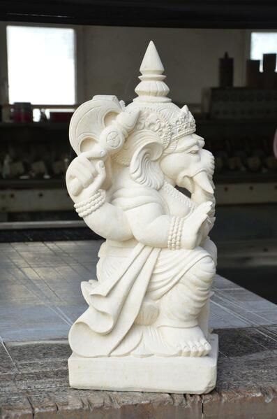 Eine weiße Statue einer Gottheit, die auf einem Tisch sitzt