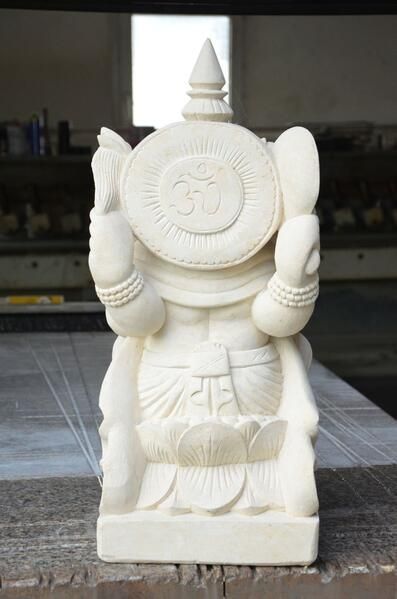 Eine weiße Statue einer Gottheit sitzt auf einem Holztisch.