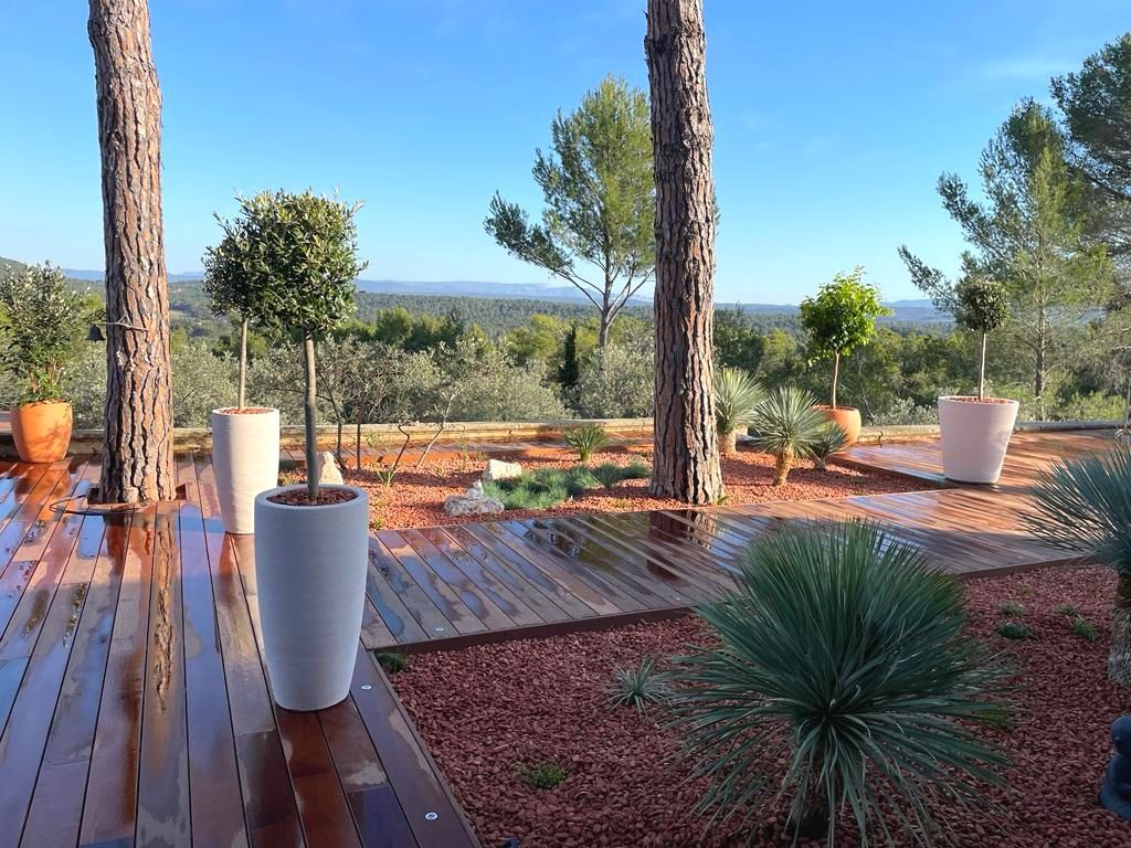 Terrasse en bois mouillée avec des arbres et des pots à le Tholonet