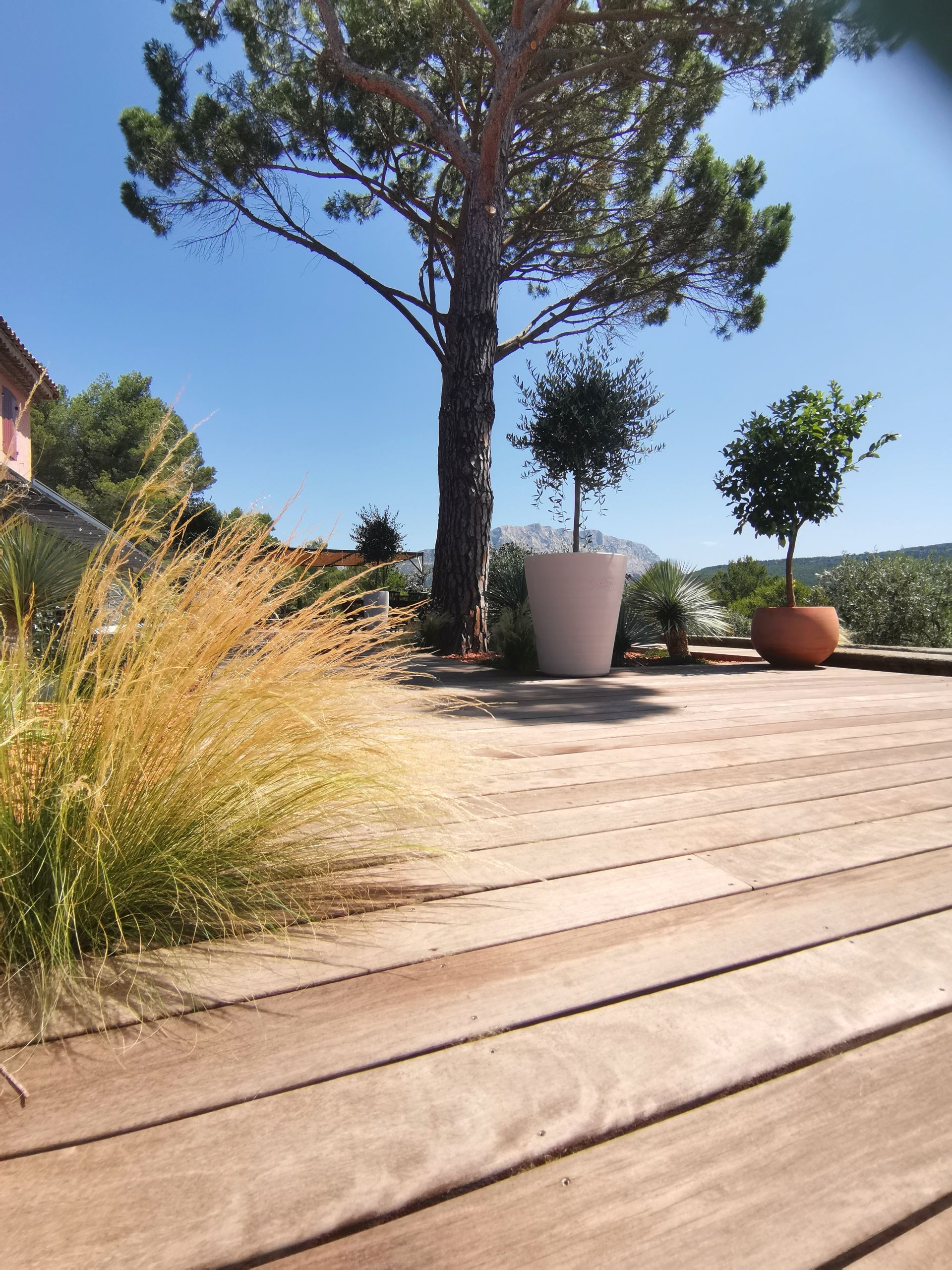 Terrasse en bois avec des pots et des arbres à le Tholonet