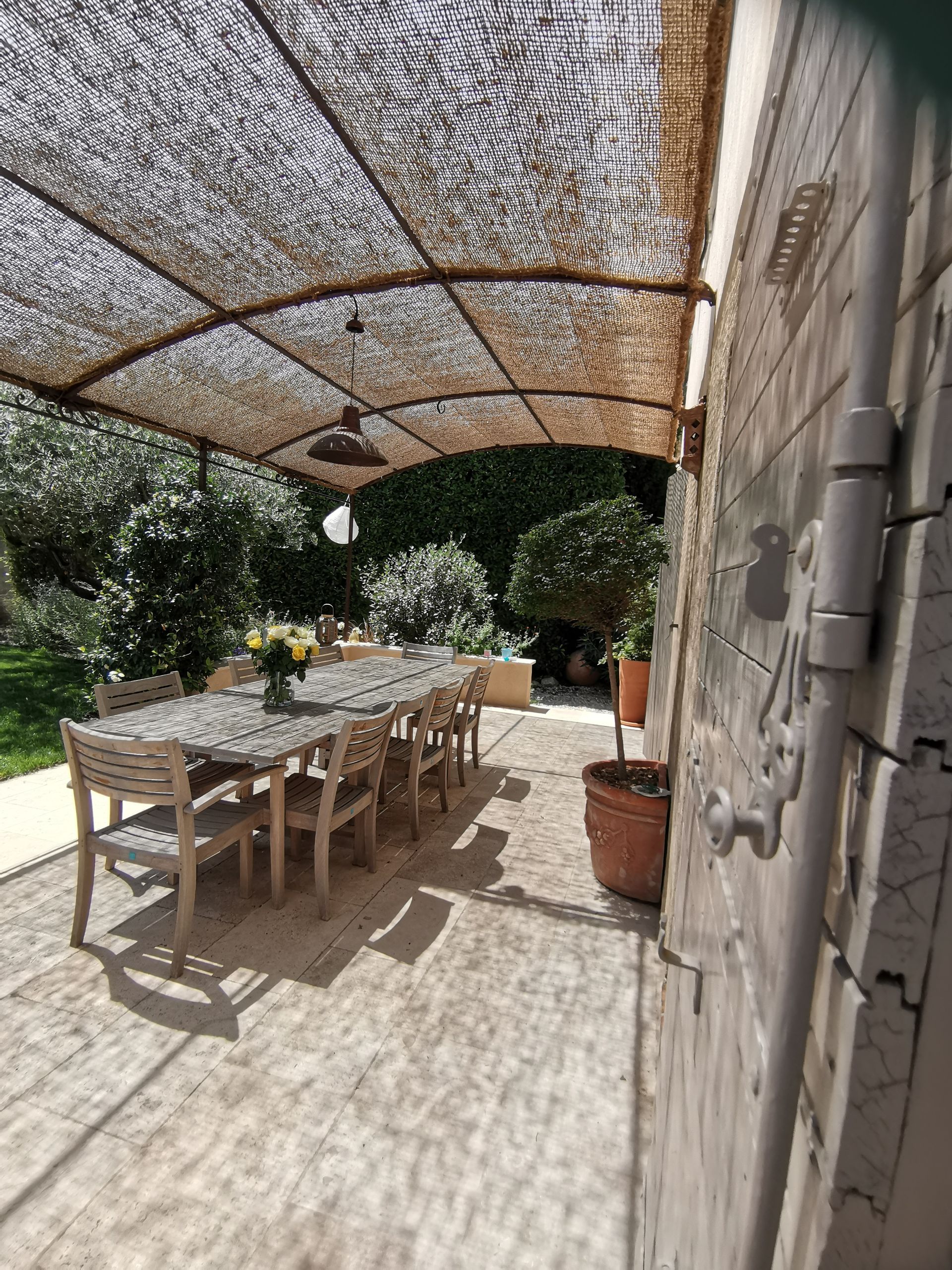 Grande table de jardin en bois sur terrasse de maison sous pergola à Aix-en-Provence