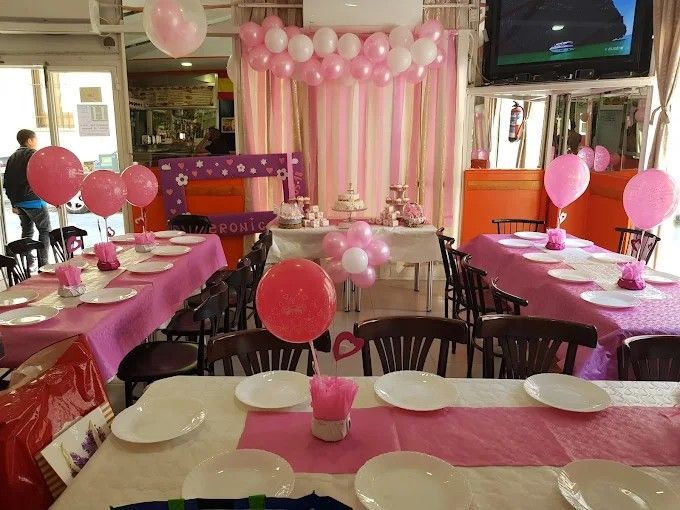 Mesas de fiesta decoradas en color rosa, con globos y pastel.