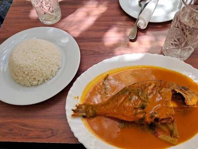 Pescado en salsa de naranja y arroz blanco sobre una mesa.
