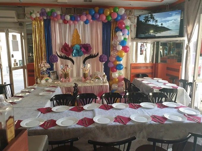 Mesa de fiesta decorada con temática de unicornio, globos y tv de fondo.