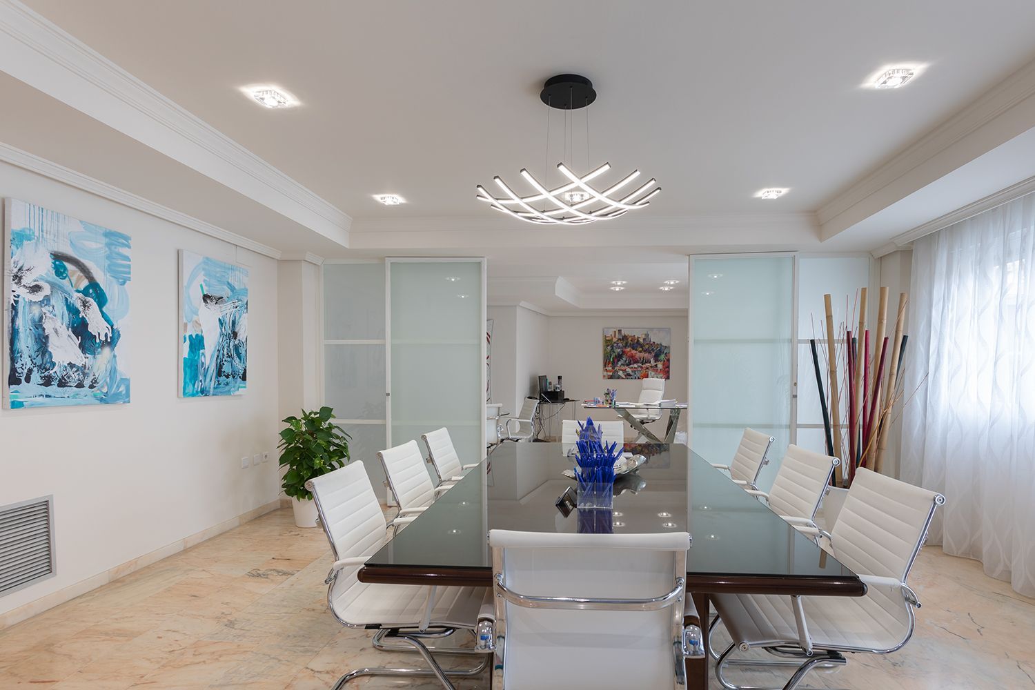 Una sala de conferencias con una mesa larga y sillas blancas.