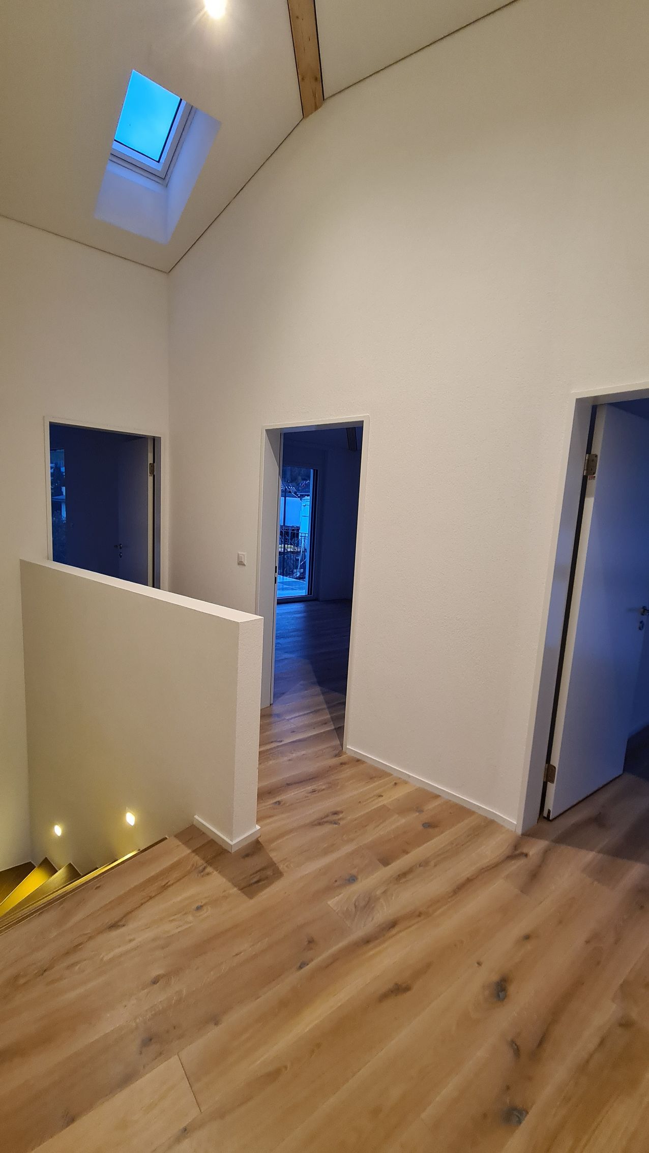 Innenflur mit Holzböden, weißen Wänden und Türen. Oberlicht.