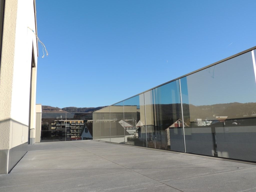 Ein Balkon mit einem Glasgeländer und einem Gebäude im Hintergrund