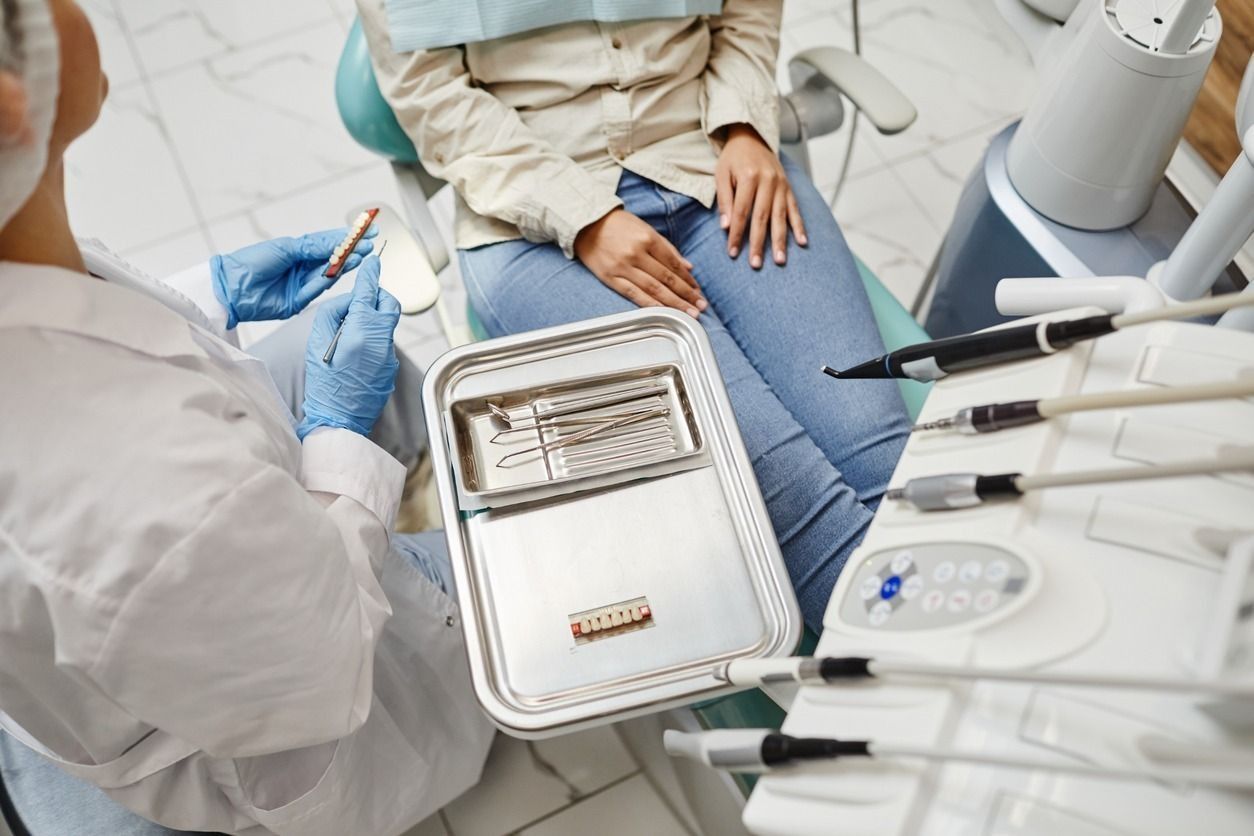 Una mujer está sentada en una silla dental mientras un dentista le examina los dientes.