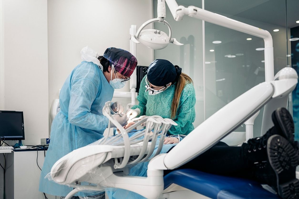 Dos dentistas están trabajando con un paciente en una silla dental.