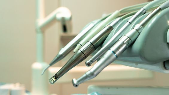 Un montón de instrumentos dentales cuelgan de una silla dental.