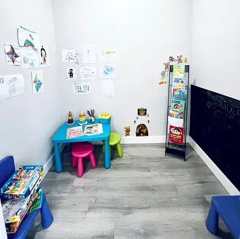 Una sala de espera para niños con mesa y sillas.