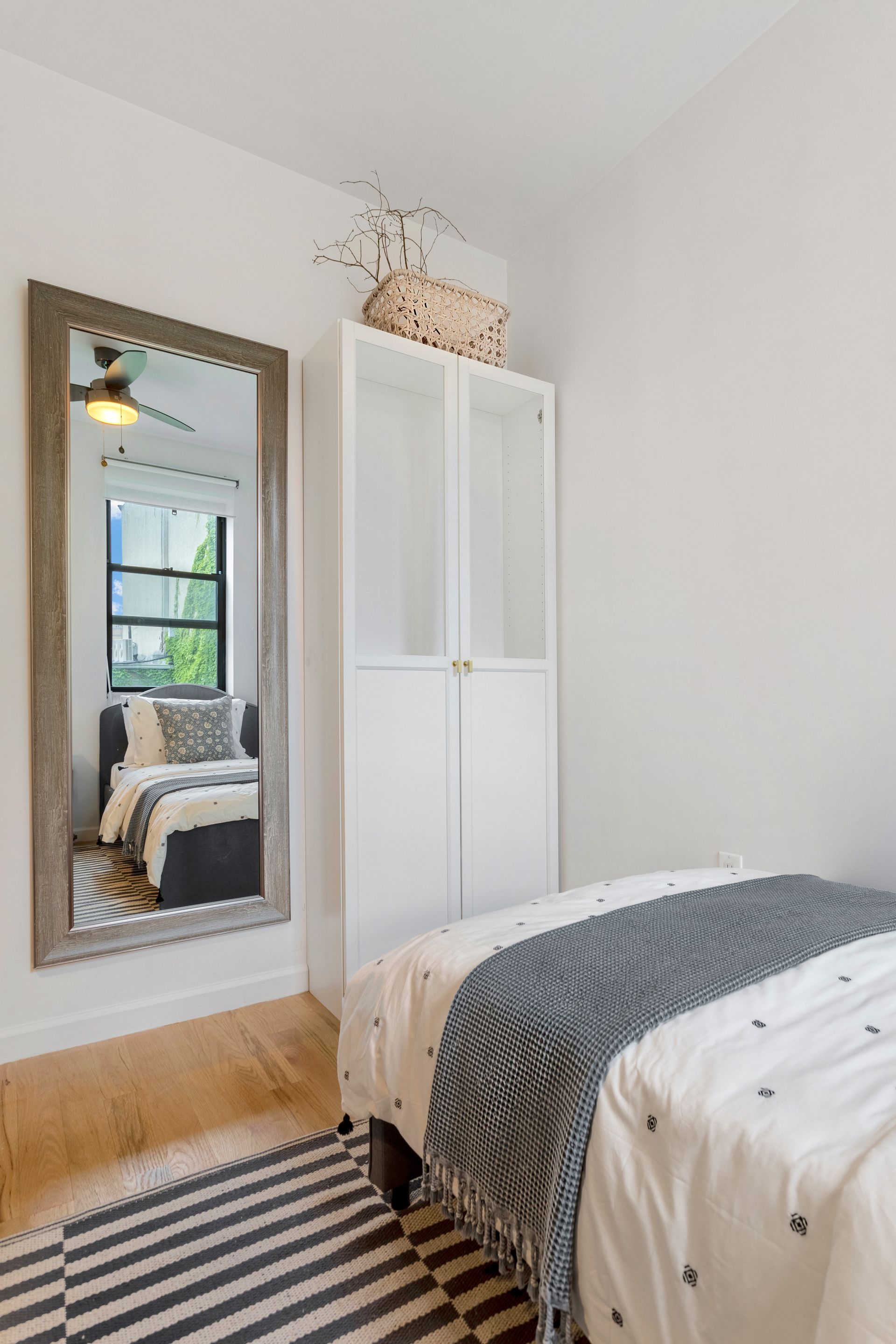 A bedroom with a bed , a large mirror and a striped rug.