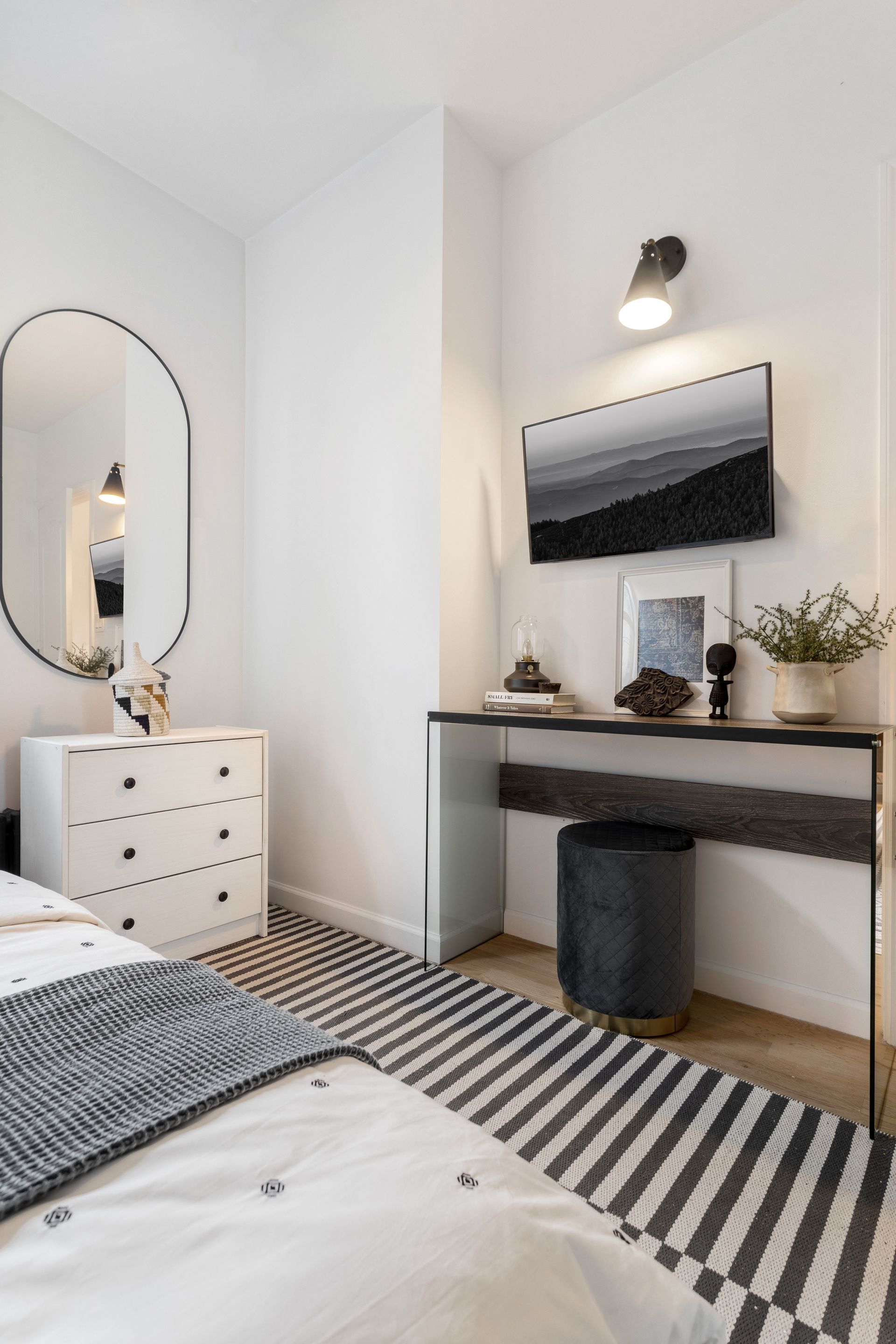 A bedroom with a bed , dresser , mirror and vanity.