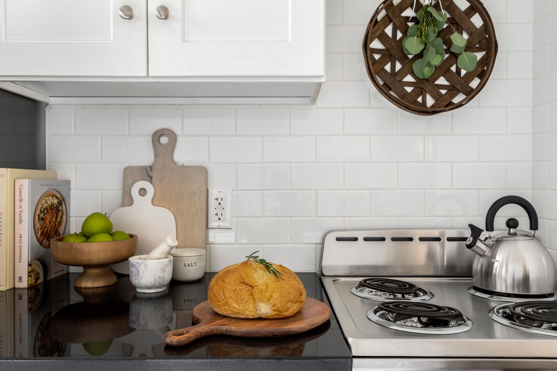 There is a loaf of bread on a wooden cutting board on the stove.