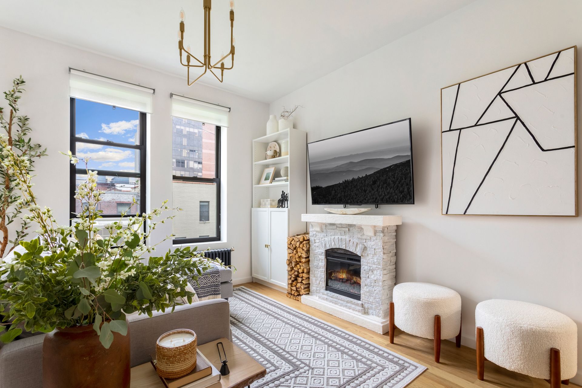 A living room with a couch , fireplace , television and paintings on the wall.