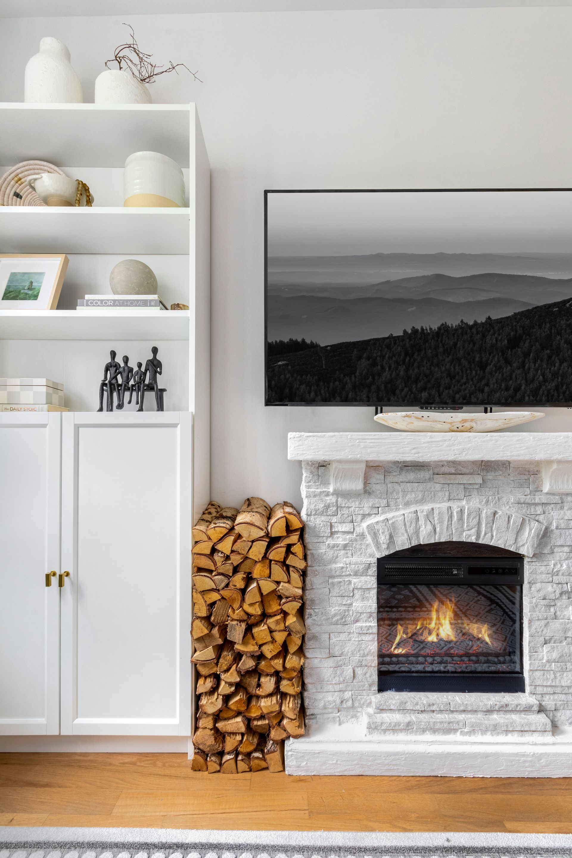 A living room with a fireplace , shelves , and a flat screen tv.