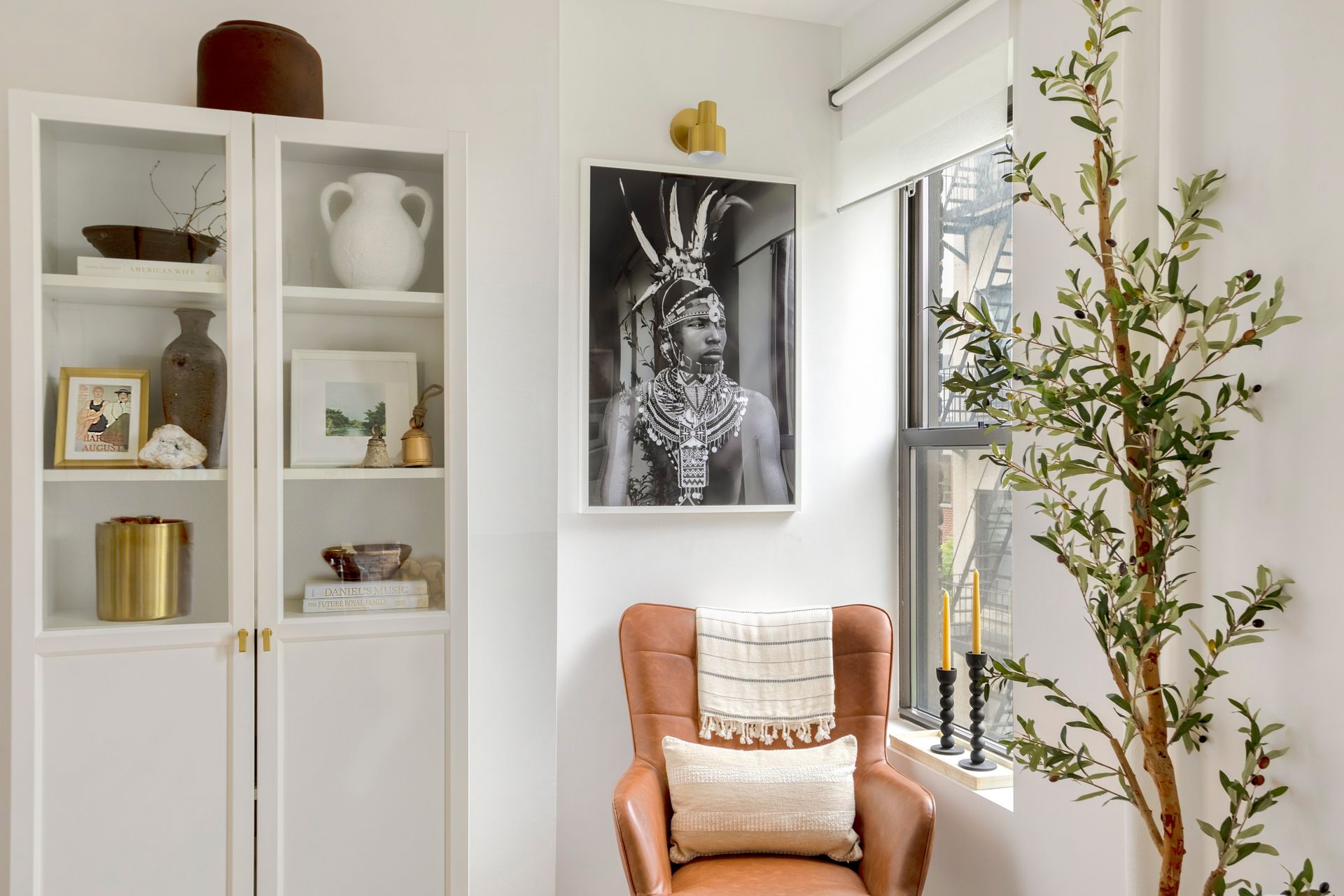 A living room with a chair , bookshelf , and a tree.