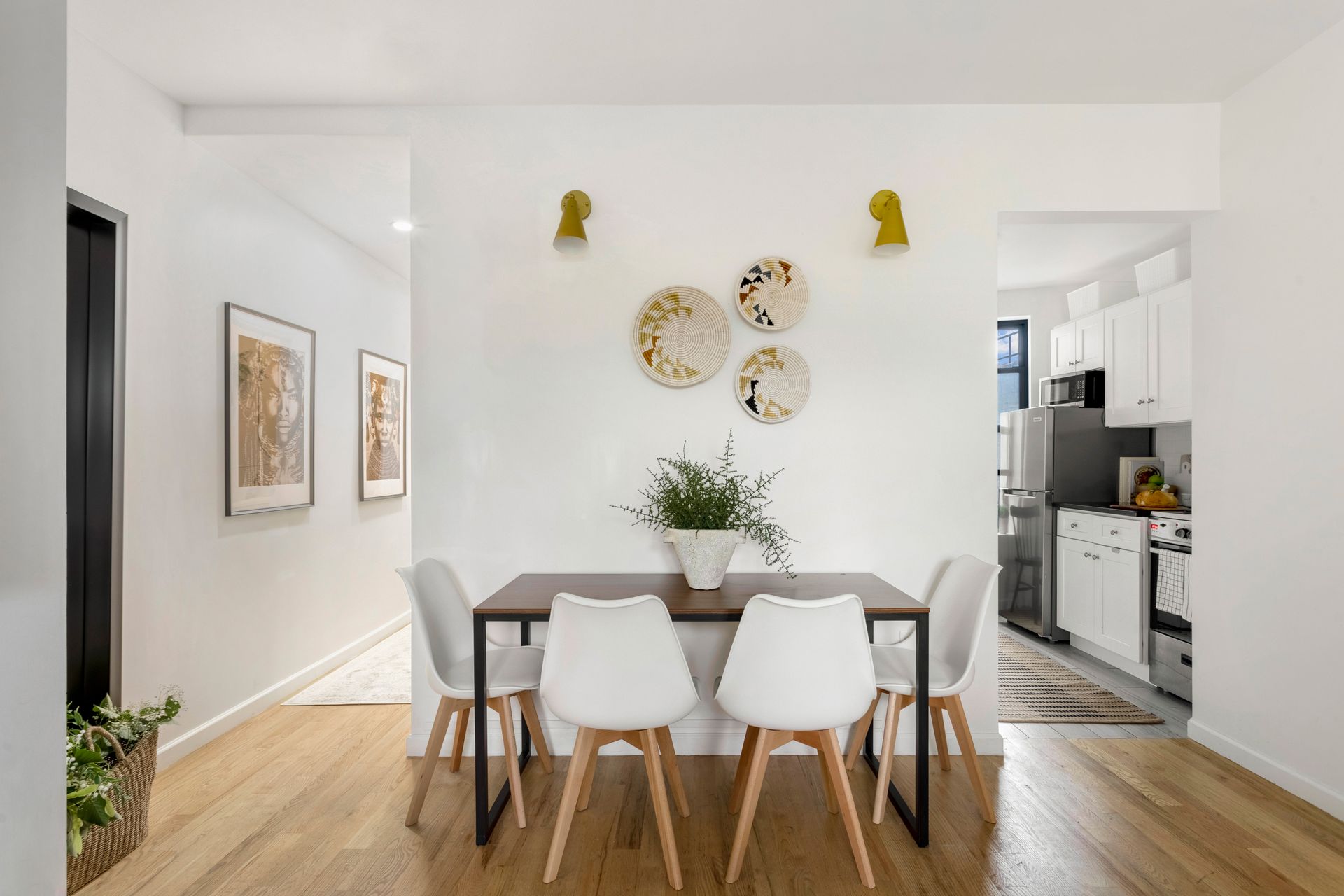 A dining room with a table and chairs and plates on the wall.