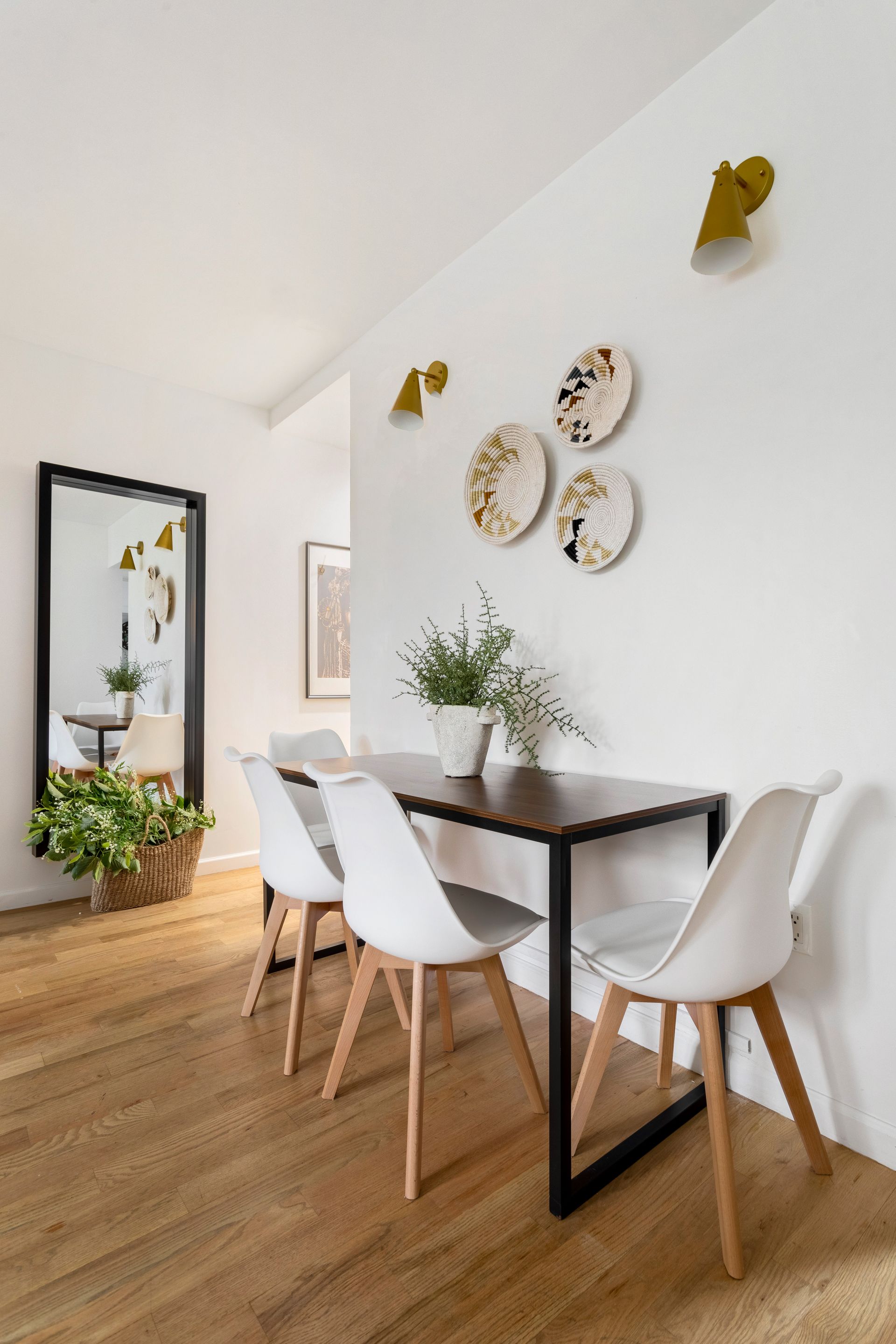 A dining room with a table and chairs and a mirror.