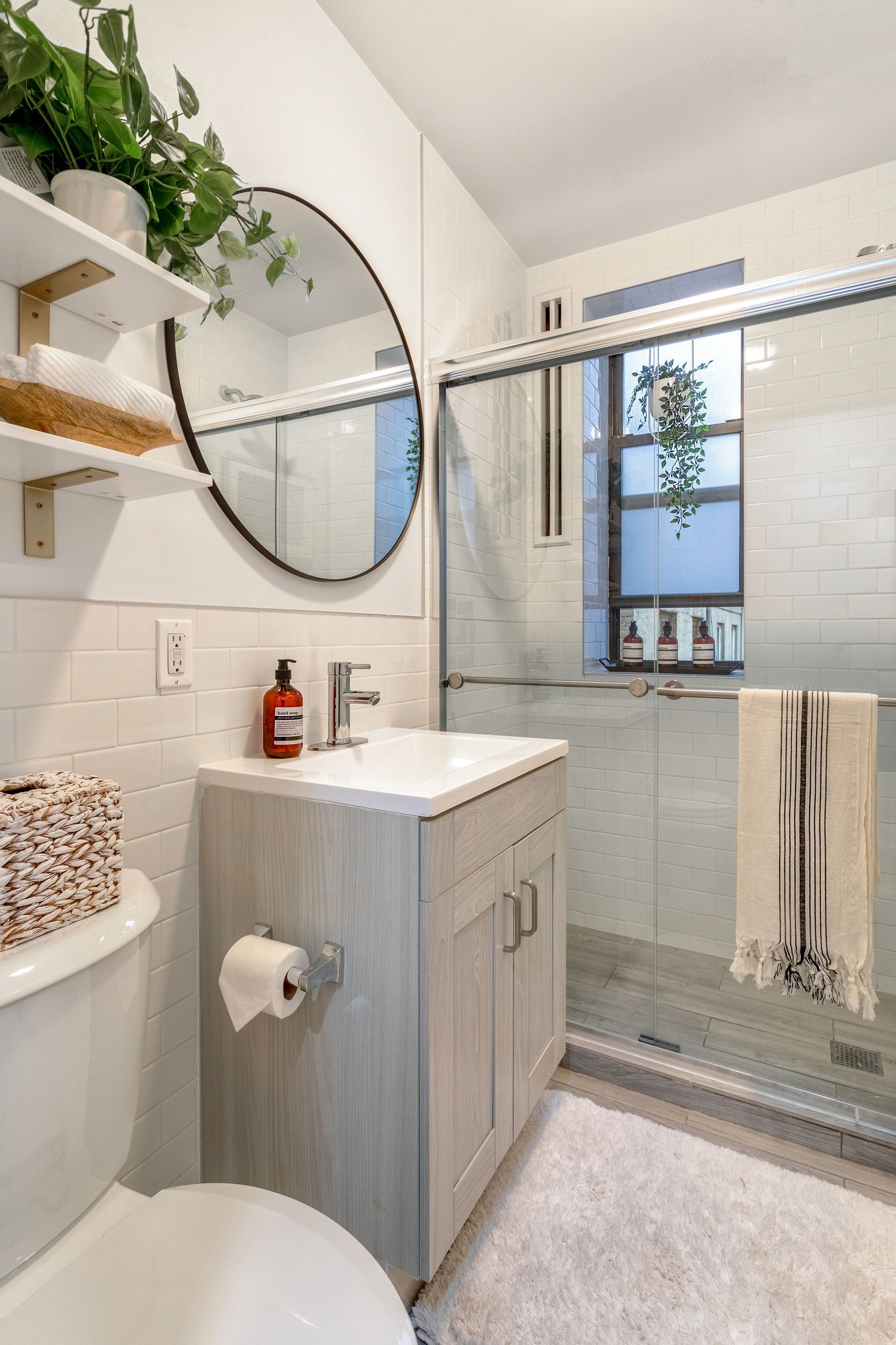 A bathroom with a toilet , sink , mirror and shower.