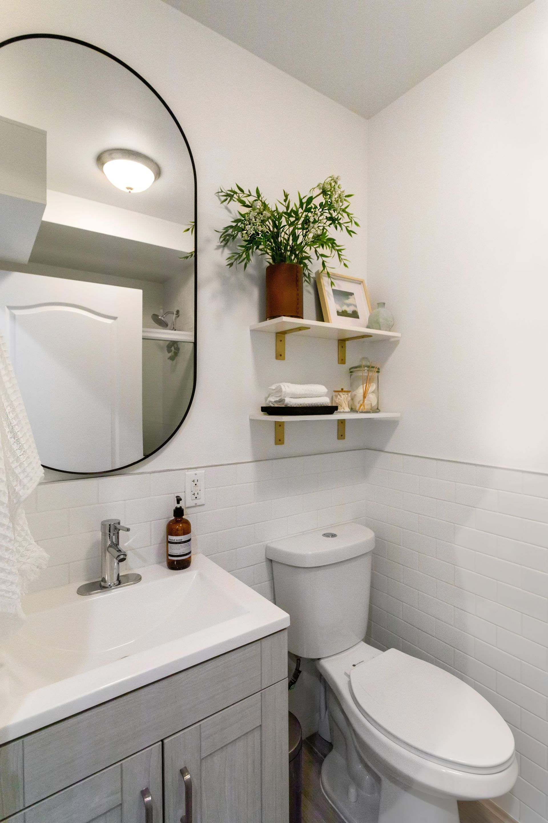 A bathroom with a toilet , sink and mirror.