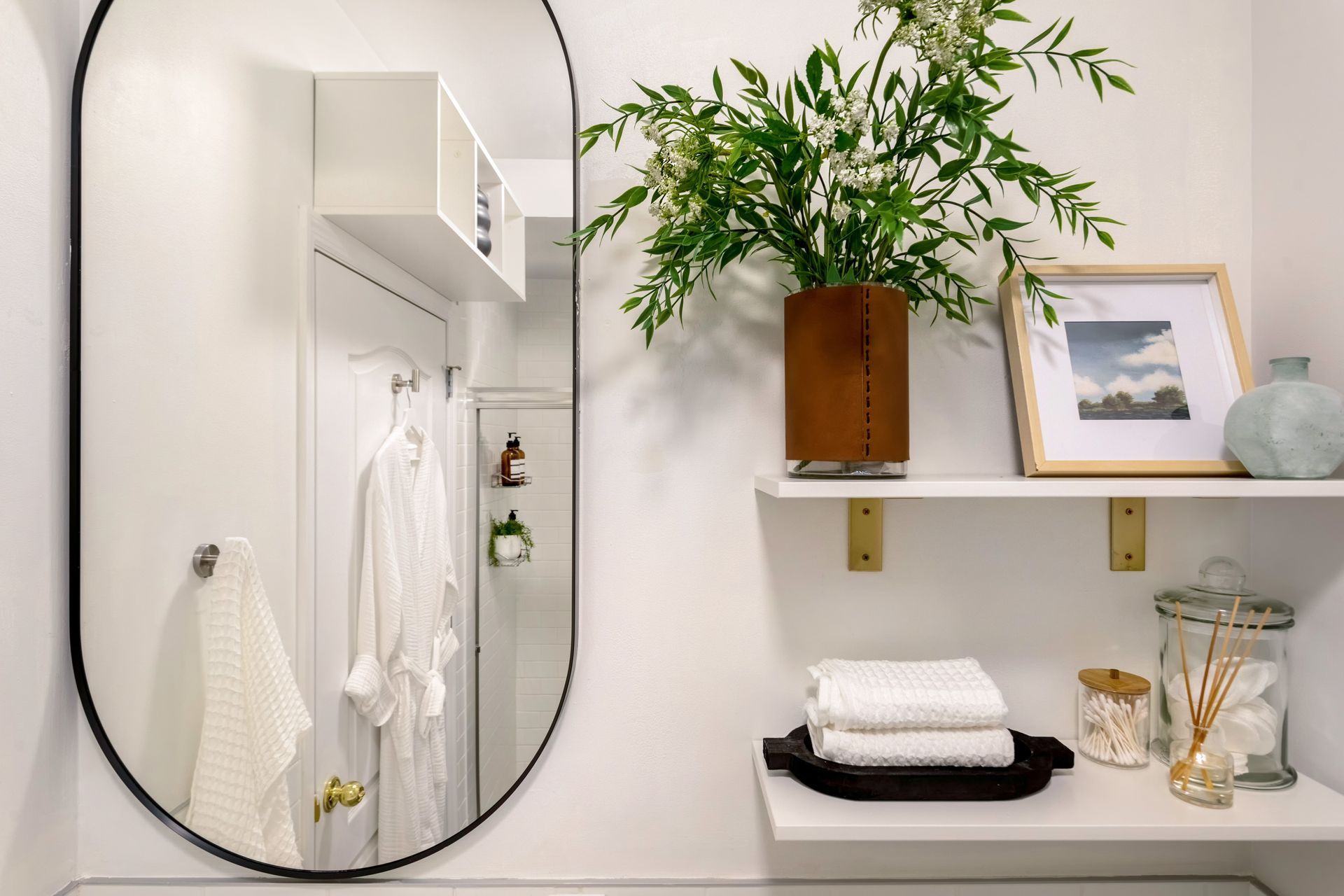 A bathroom with a large mirror and a shelf with towels.