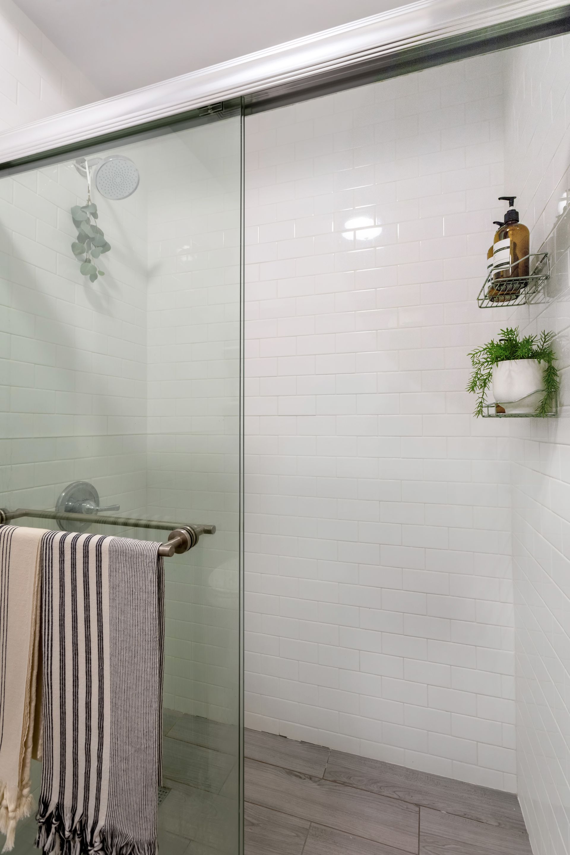 A bathroom with a sliding glass shower door and a towel rack.