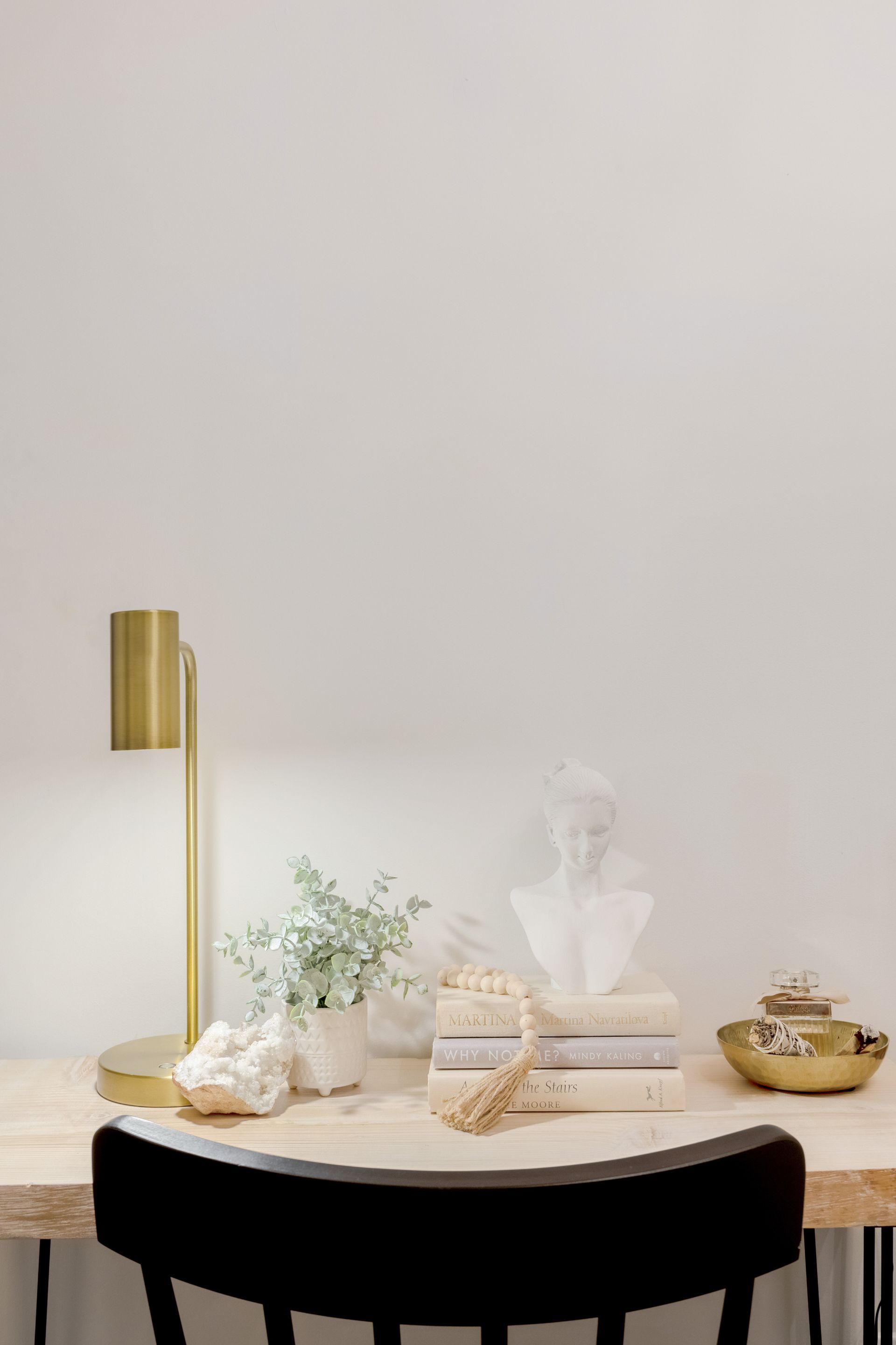 A desk with a lamp and a stack of books on it.