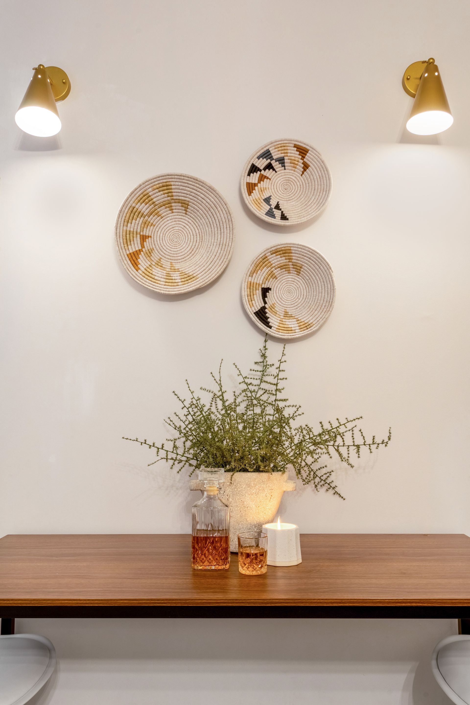 A table with plates on the wall and a plant on it.