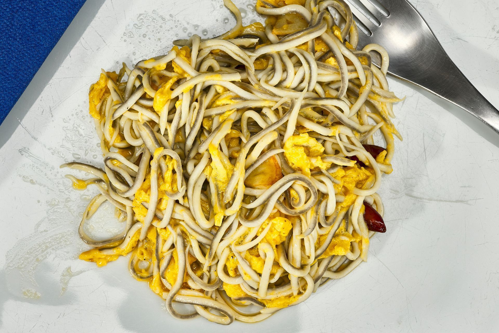 Plato de angulas con huevos revueltos en un plato blanco.